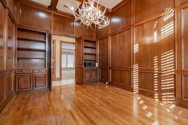 interior space featuring wood walls, light wood-type flooring, and an inviting chandelier