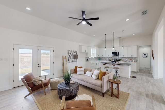 living room with french doors, ceiling fan, light hardwood / wood-style flooring, and vaulted ceiling