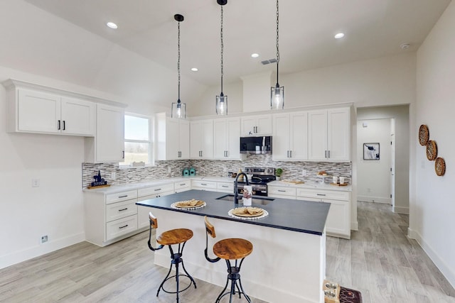 kitchen featuring white cabinetry, light hardwood / wood-style flooring, an island with sink, and appliances with stainless steel finishes