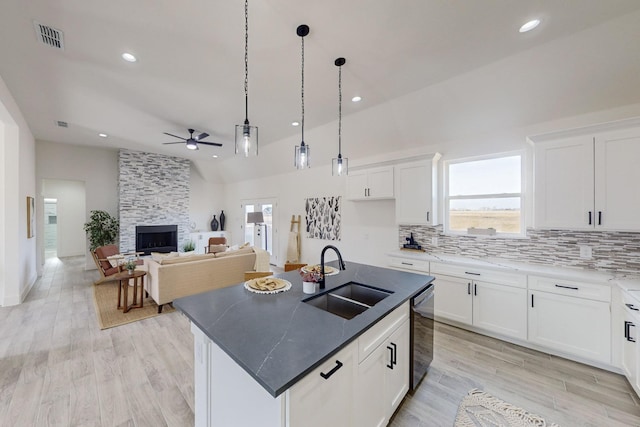 kitchen featuring a kitchen island with sink, sink, white cabinets, light hardwood / wood-style floors, and lofted ceiling