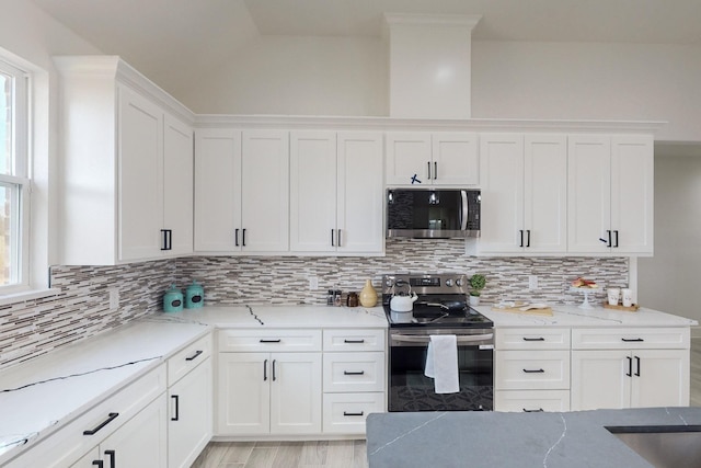 kitchen featuring backsplash, stainless steel appliances, white cabinetry, and plenty of natural light