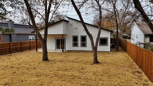 rear view of house with central AC and a lawn