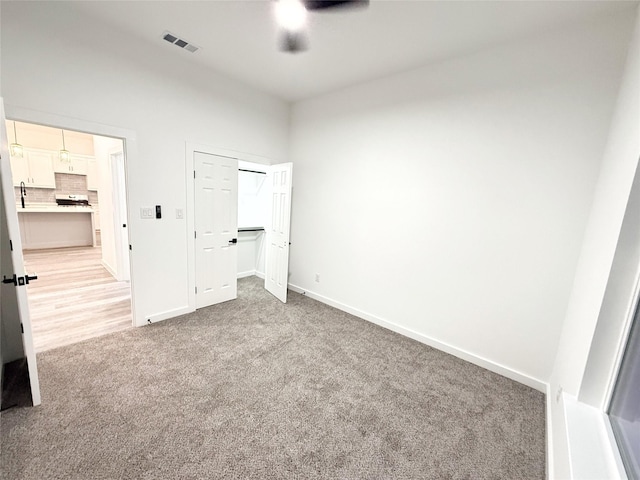 unfurnished bedroom with ceiling fan, a closet, and light carpet