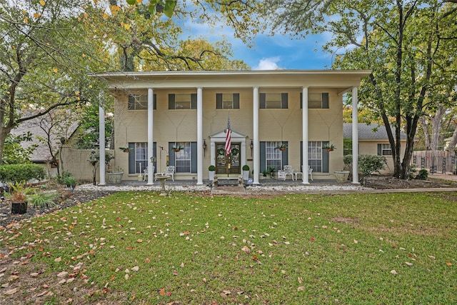 greek revival inspired property with a front yard and a porch