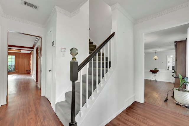 stairs featuring hardwood / wood-style floors and crown molding