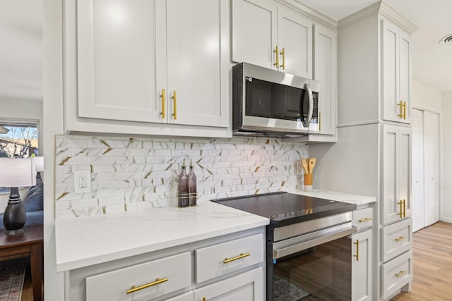 kitchen with light hardwood / wood-style flooring, decorative backsplash, light stone countertops, appliances with stainless steel finishes, and white cabinetry