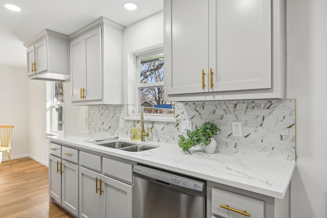 kitchen featuring dishwasher, backsplash, sink, light hardwood / wood-style flooring, and light stone counters