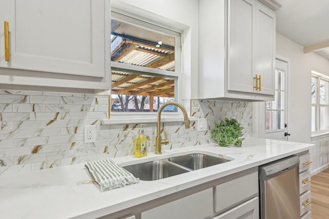 kitchen featuring stainless steel dishwasher, decorative backsplash, light stone countertops, and sink