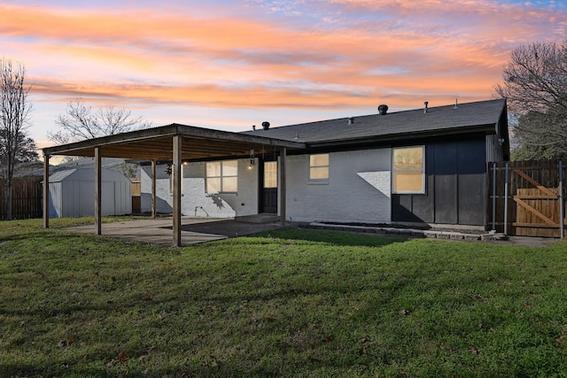 back house at dusk with a shed, a yard, and a patio