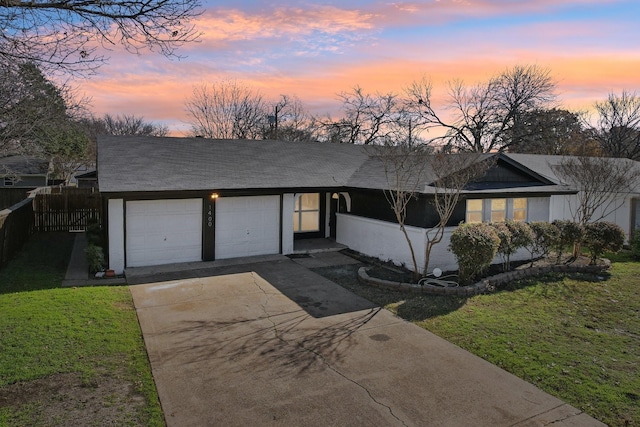 ranch-style home featuring a lawn and a garage