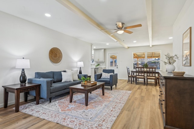 living room with beamed ceiling, light hardwood / wood-style floors, and ceiling fan