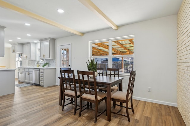 dining space with beamed ceiling and light wood-type flooring