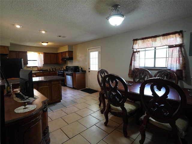 dining area featuring plenty of natural light, light tile patterned flooring, sink, and a textured ceiling