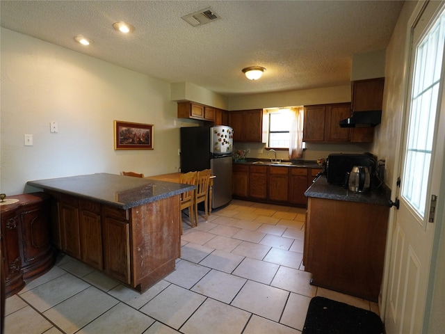 kitchen featuring kitchen peninsula, a textured ceiling, sink, stainless steel refrigerator, and light tile patterned flooring