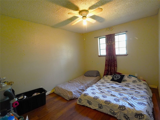 bedroom with hardwood / wood-style floors, ceiling fan, and a textured ceiling