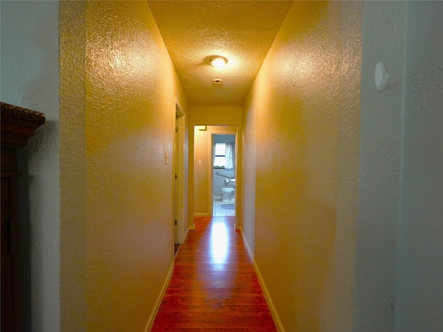 corridor with wood-type flooring and a textured ceiling