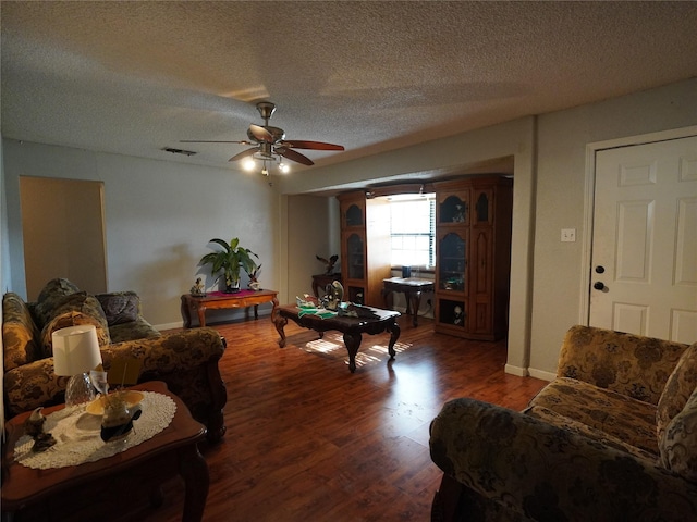 living room featuring ceiling fan, dark hardwood / wood-style flooring, and a textured ceiling