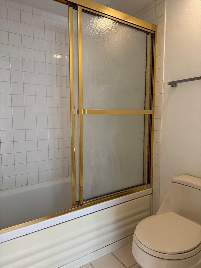 bathroom featuring toilet, tile patterned floors, and bath / shower combo with glass door