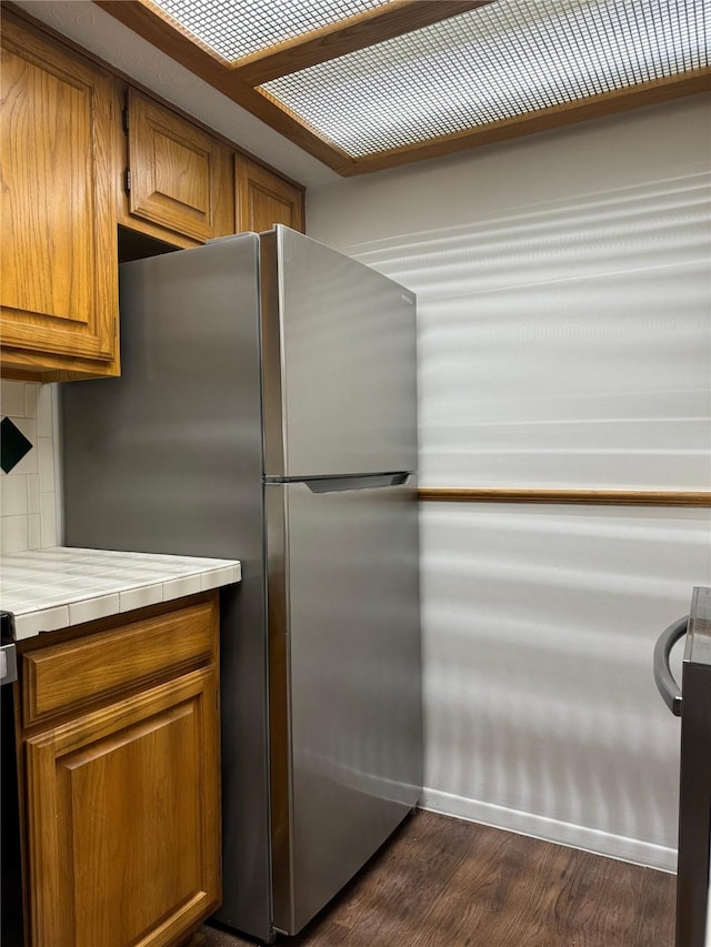 kitchen with tasteful backsplash, stainless steel fridge, tile counters, and dark hardwood / wood-style floors