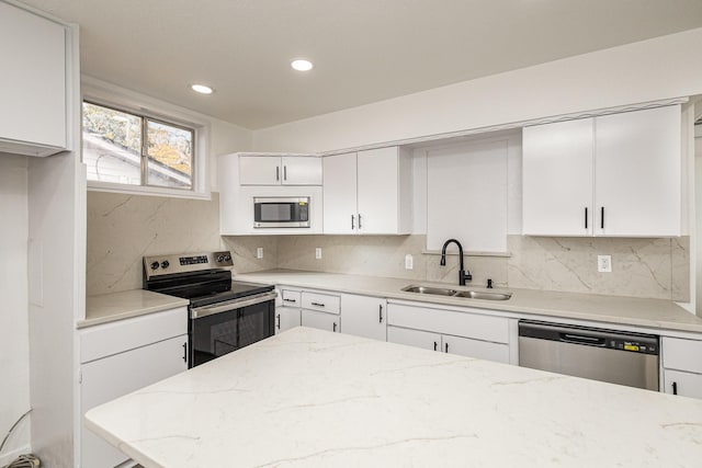 kitchen featuring white cabinetry, sink, light stone counters, and appliances with stainless steel finishes