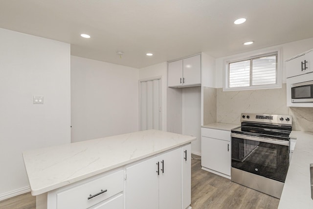 kitchen with light stone countertops, a center island, light hardwood / wood-style floors, white cabinets, and appliances with stainless steel finishes