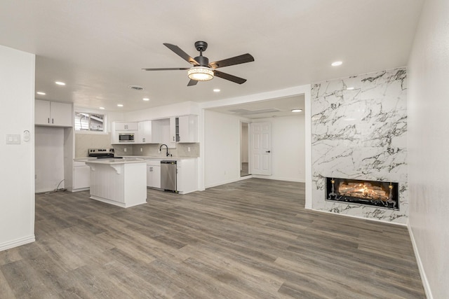 kitchen featuring a high end fireplace, a kitchen island, dark hardwood / wood-style flooring, white cabinetry, and stainless steel appliances