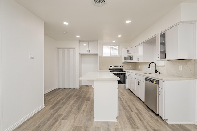 kitchen with white cabinetry, sink, stainless steel appliances, light hardwood / wood-style flooring, and a kitchen island