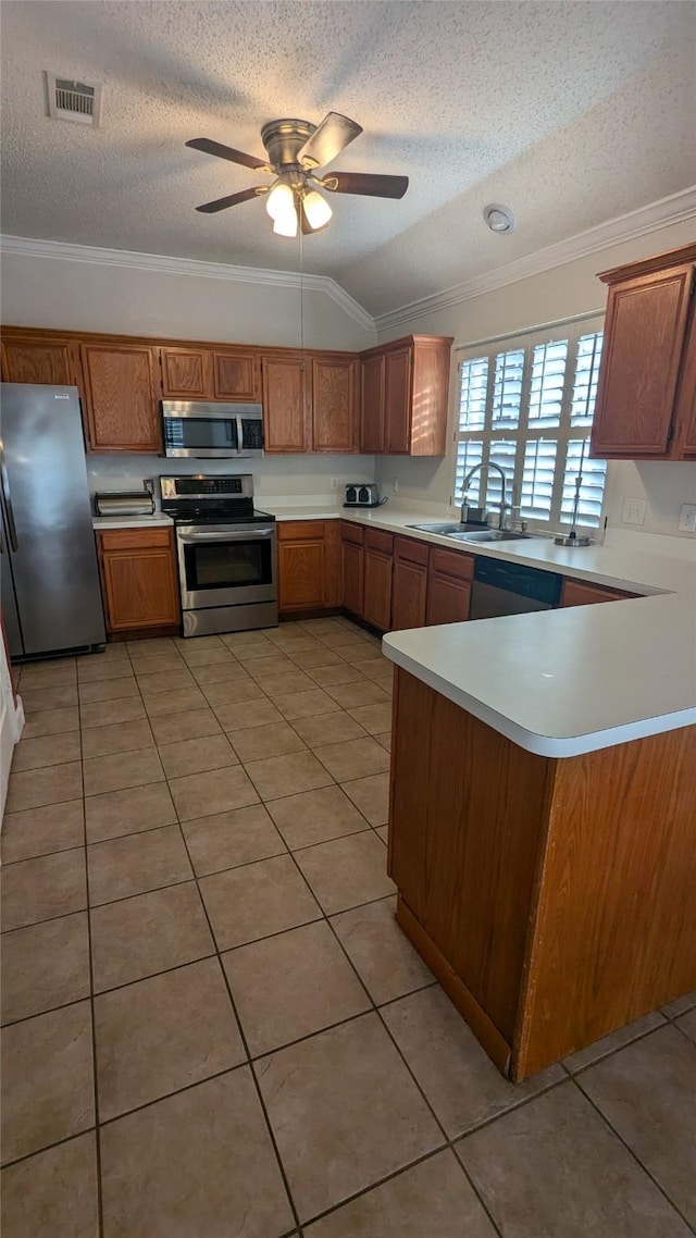 kitchen with sink, kitchen peninsula, lofted ceiling, light tile patterned flooring, and appliances with stainless steel finishes