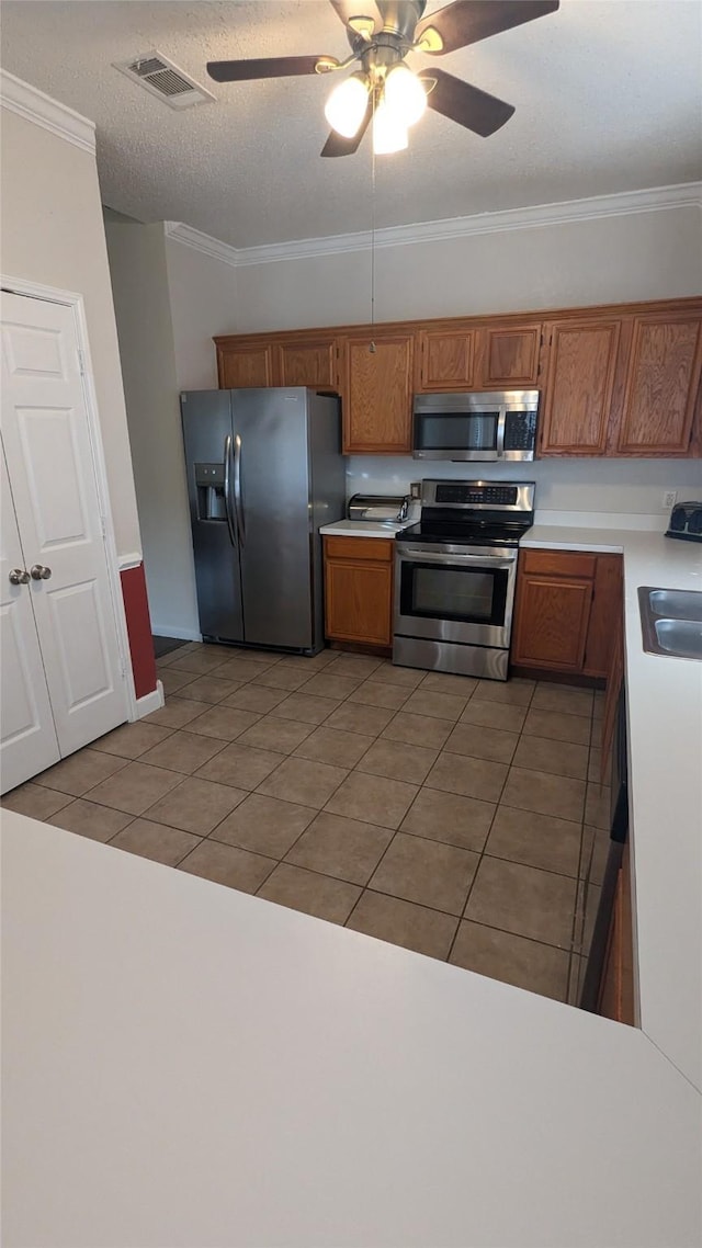 kitchen with sink, ceiling fan, ornamental molding, light tile patterned flooring, and stainless steel appliances