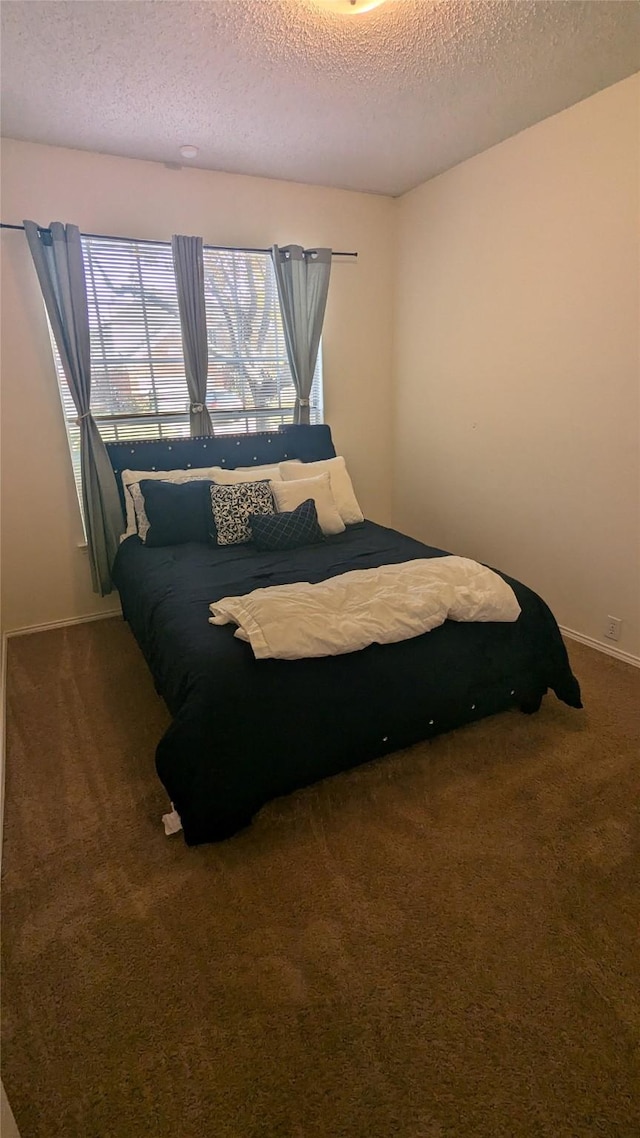 bedroom with dark colored carpet and a textured ceiling