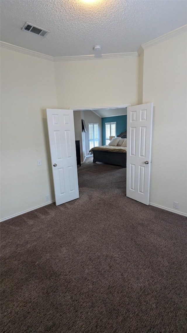 unfurnished room with ornamental molding, a textured ceiling, and dark colored carpet