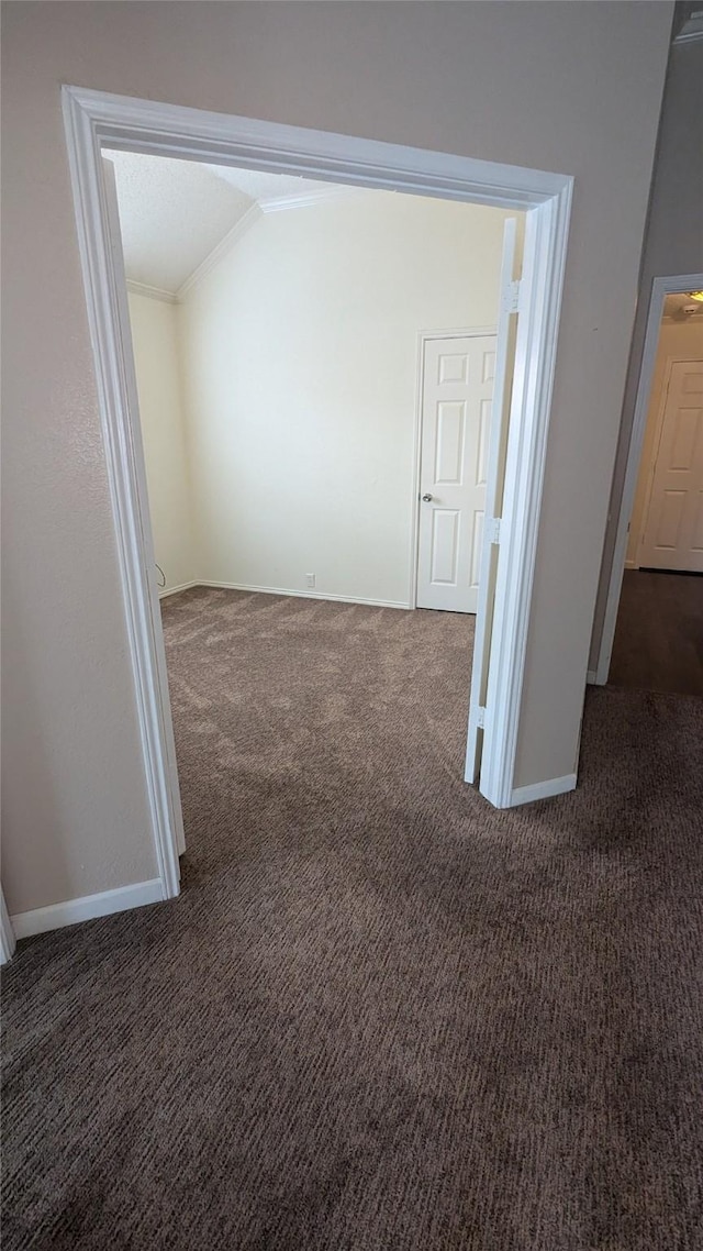 unfurnished room with crown molding, lofted ceiling, and dark colored carpet