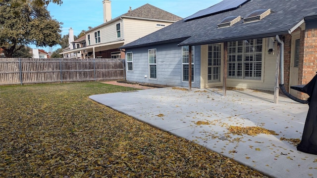 rear view of house featuring solar panels, a patio area, and a lawn