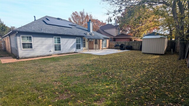 back of property with a lawn, a storage unit, a patio area, and solar panels