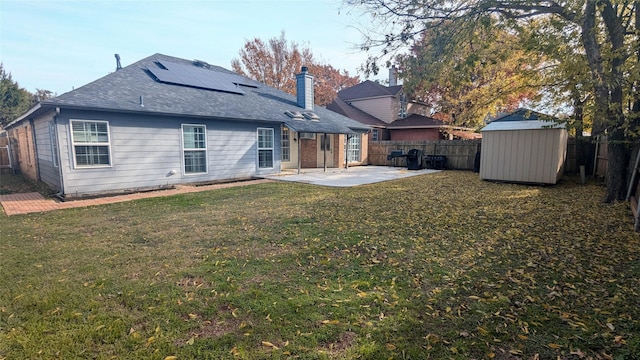 back of property with a lawn, a storage unit, a patio area, and solar panels