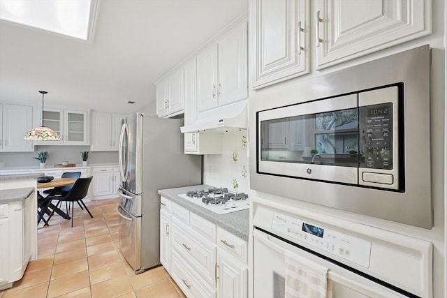 kitchen with white cabinetry, appliances with stainless steel finishes, decorative light fixtures, light tile patterned flooring, and custom exhaust hood