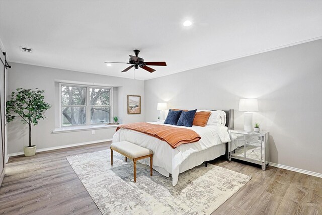 bedroom featuring ceiling fan, light hardwood / wood-style flooring, and ornamental molding