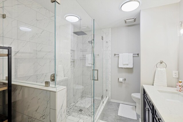 bathroom with a shower with door, vanity, and toilet