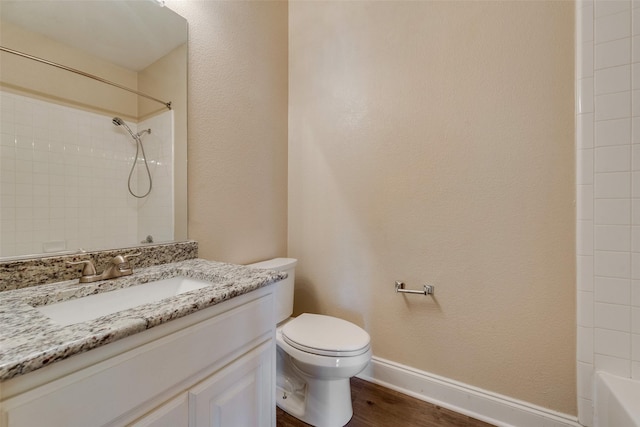 full bathroom featuring vanity, tiled shower / bath, wood-type flooring, and toilet