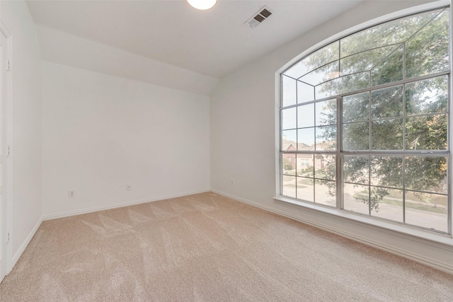 spare room featuring light colored carpet and vaulted ceiling