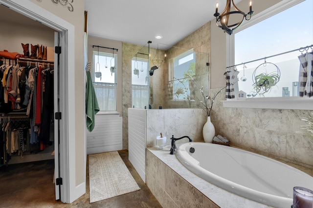 bathroom with independent shower and bath, concrete flooring, a wealth of natural light, and a chandelier