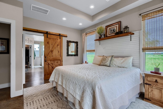 bedroom featuring a barn door and light hardwood / wood-style floors