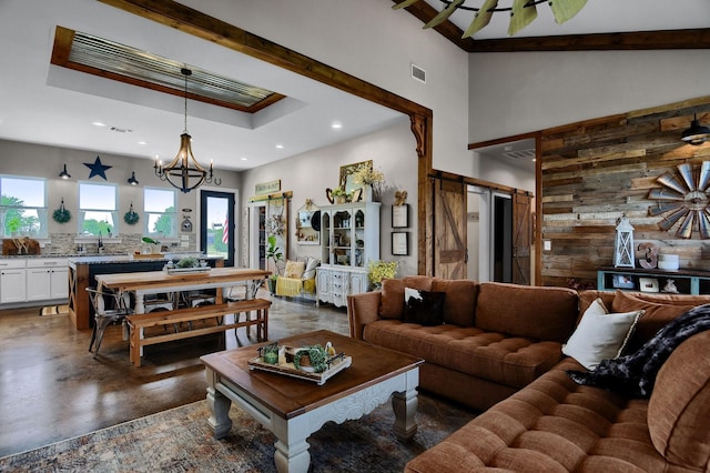 living room featuring a chandelier, a barn door, plenty of natural light, and wood walls