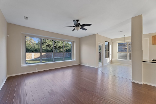 unfurnished living room featuring hardwood / wood-style floors and ceiling fan with notable chandelier