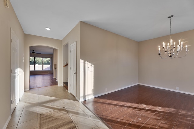 interior space with ceiling fan with notable chandelier and light wood-type flooring