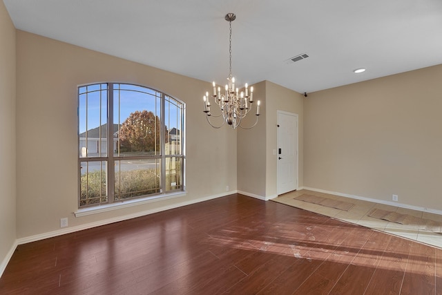 unfurnished room featuring hardwood / wood-style floors and an inviting chandelier