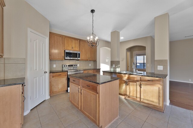 kitchen featuring sink, hanging light fixtures, dark stone countertops, kitchen peninsula, and stainless steel appliances