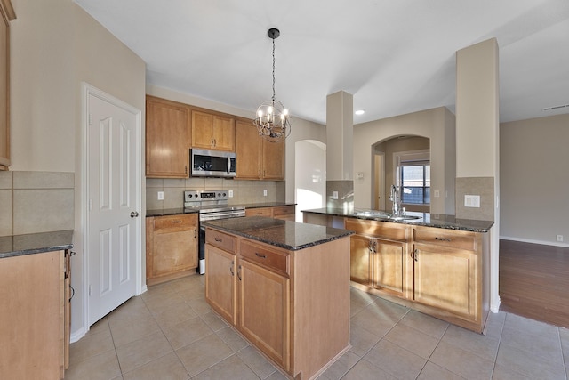 kitchen featuring sink, hanging light fixtures, dark stone countertops, kitchen peninsula, and stainless steel appliances