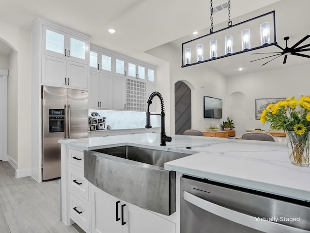 kitchen with ceiling fan, sink, hanging light fixtures, stainless steel appliances, and white cabinets