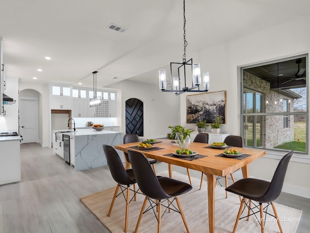 dining space with a notable chandelier, light hardwood / wood-style floors, and sink